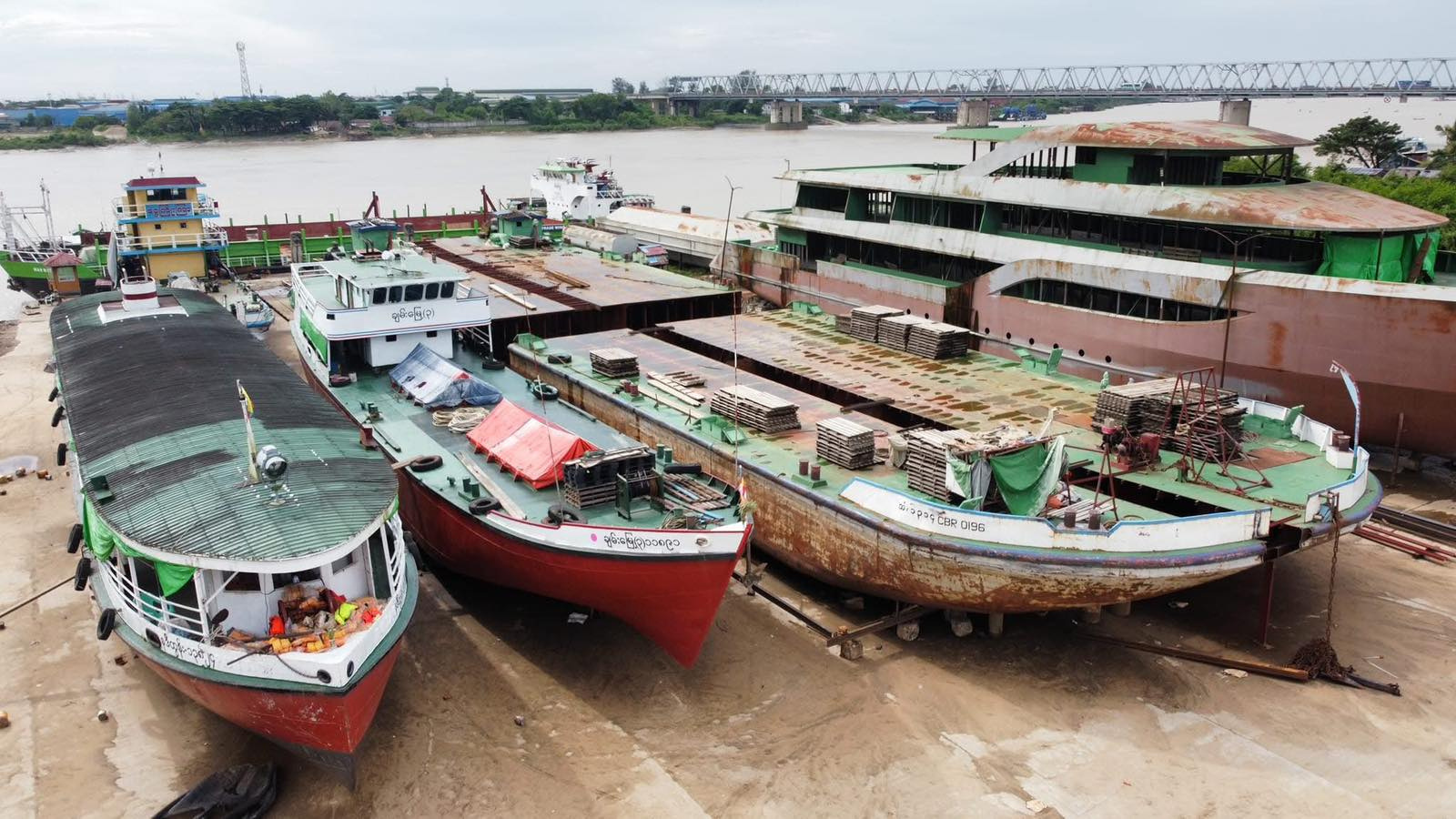 Large vessels resting in a shipyard beside a river